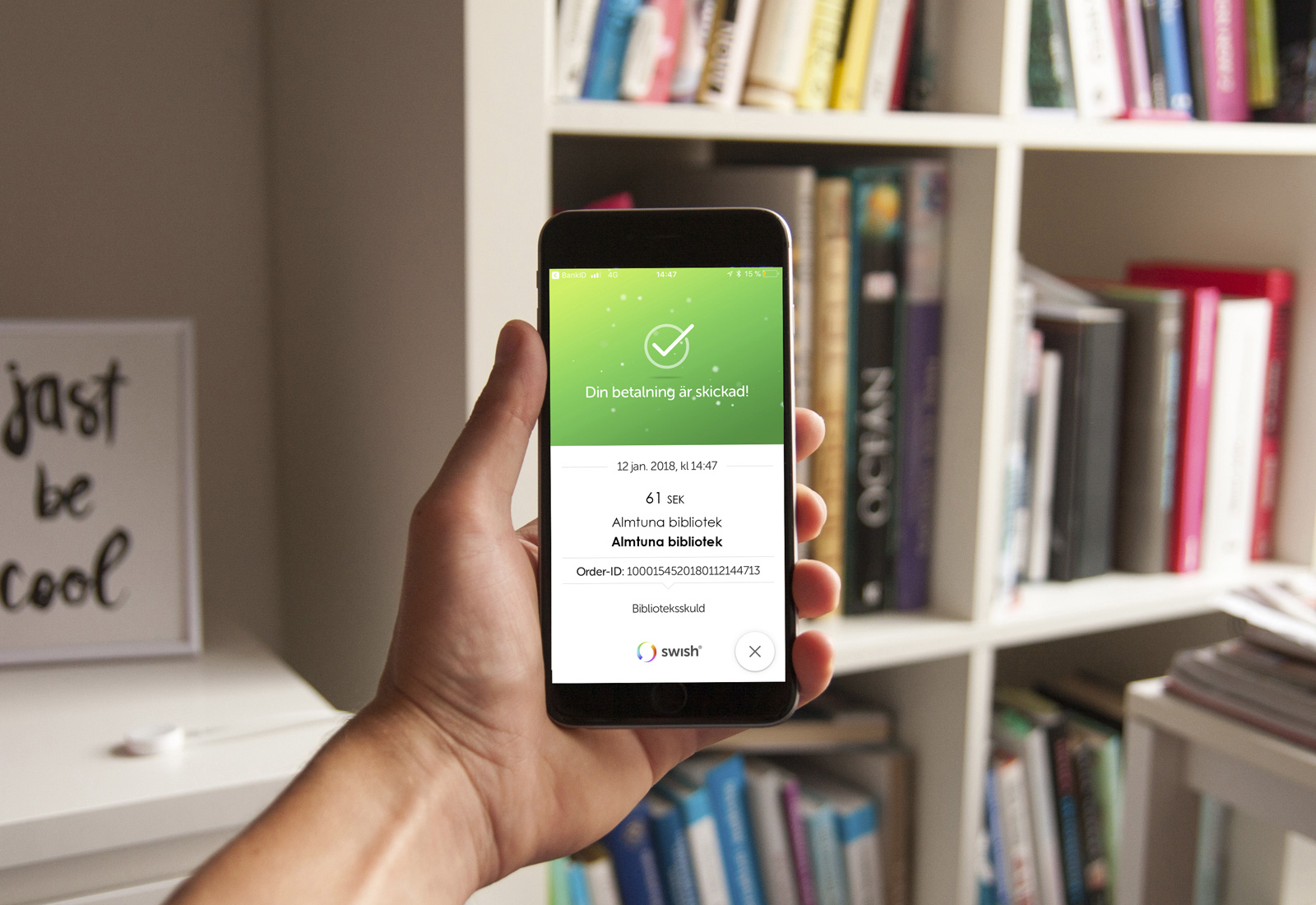 Hand håller telefon med Axiell pay med swish